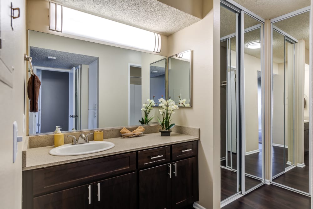 A renovated bathroom with a large vanity and a mirrored closet door at Kendallwood Apartments in Whittier, California