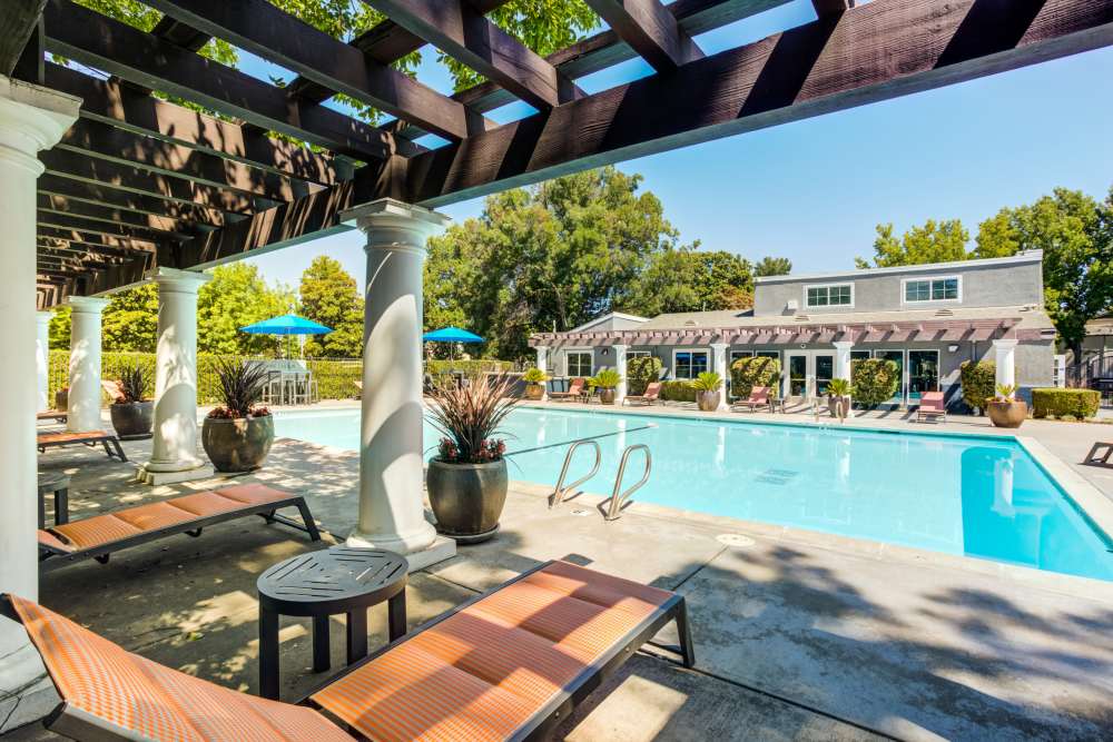 Expansive pool deck with lounge chairs at The Woodlands Apartments in Sacramento, California