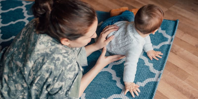 A woman in uniform sitting on the floor with her baby at Evergreen in Joint Base Lewis McChord, Washington