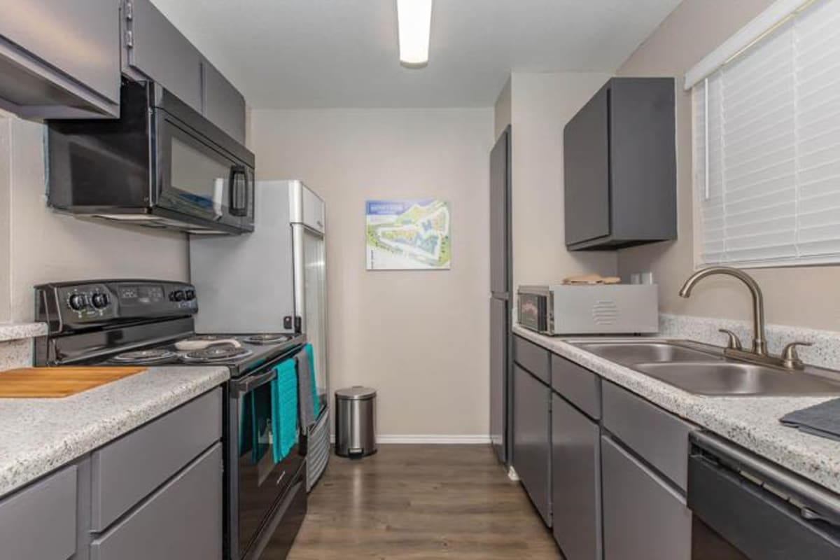 Kitchen with full cabinets, counters, microwave, and sink at Water's Edge in Corpus Christi, Texas