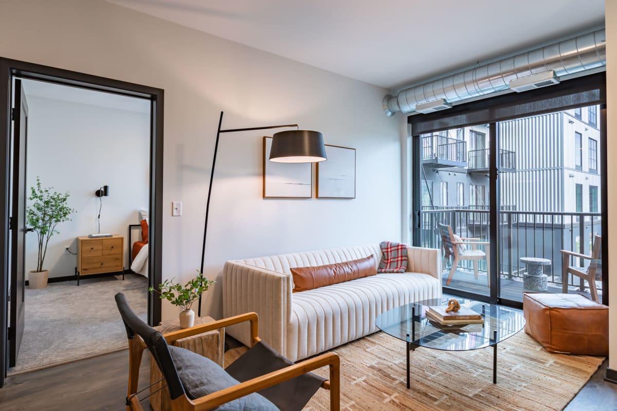 Apartment living room with a door out to a private balcony at Carbon31 in Bloomington, Minnesota