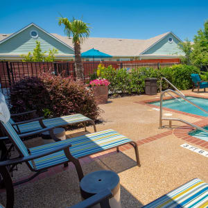 Lounging chairs outdoors on a sunny day next to a pool at Sunstone Village in Denton, Texas