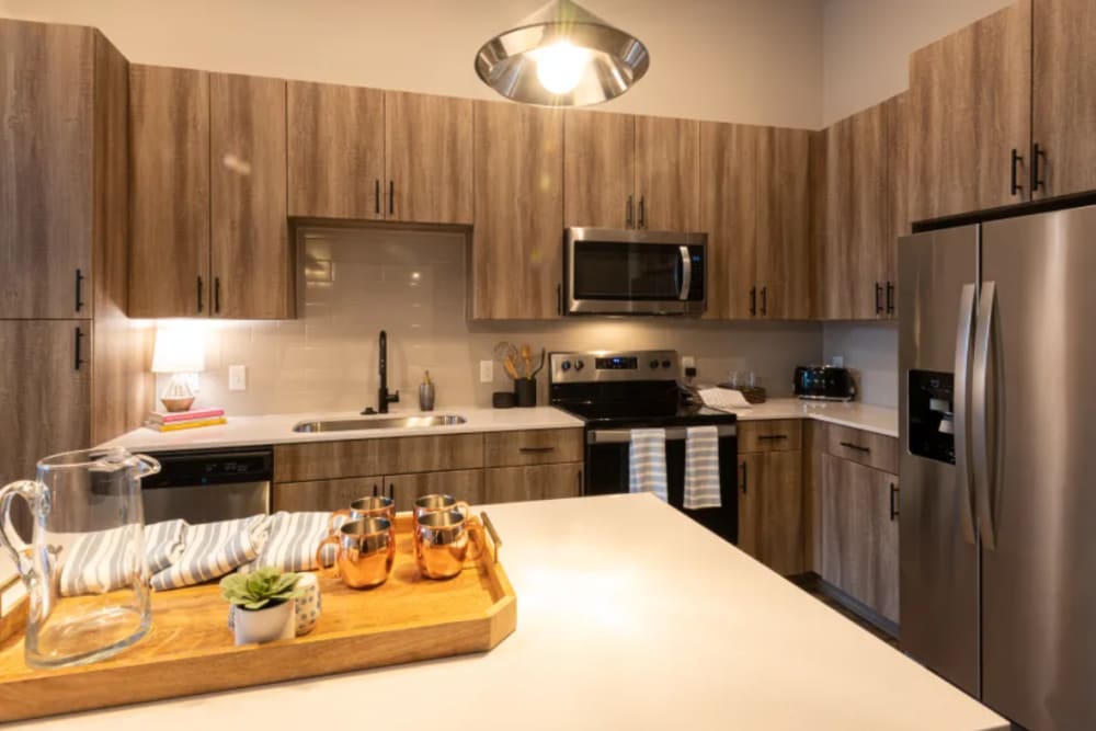 Contemporary kitchen featuring a large island, wooden cabinetry, and stainless steel appliances at The Reserve at Patterson Place in Durham, North Carolina