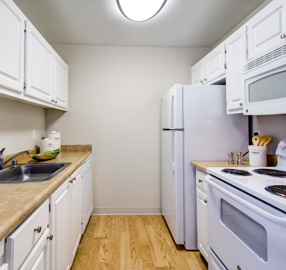 Modern kitchen with white appliances and hardwood flooring in a model home at Waterstone Fremont in Fremont, California