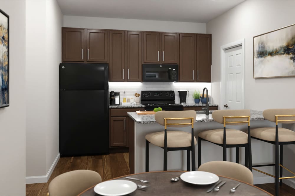 Modern apartment kitchen with custom cabinetry, black appliances, and breakfast bar seating at MainLine Apartment Homes in Fredericksburg, Virginia
