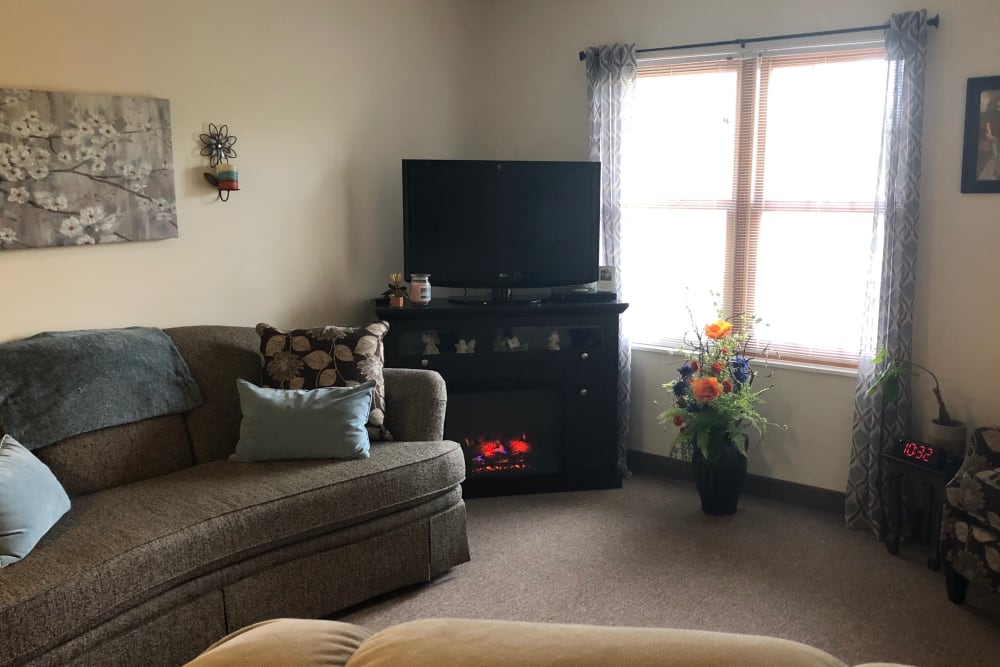 A resident living room with sofa seating and window at HeatherWood Assisted Living & Memory Care in Eau Claire, Wisconsin. 