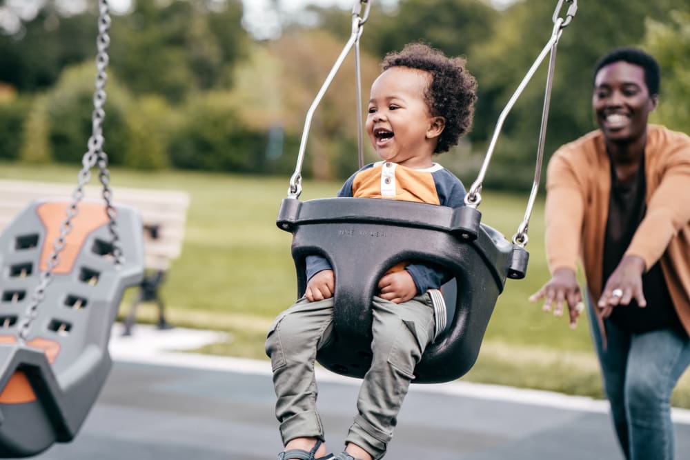 Resident pushing their child on a swing at the playground near Westover Pointe in Wilmington, Delaware