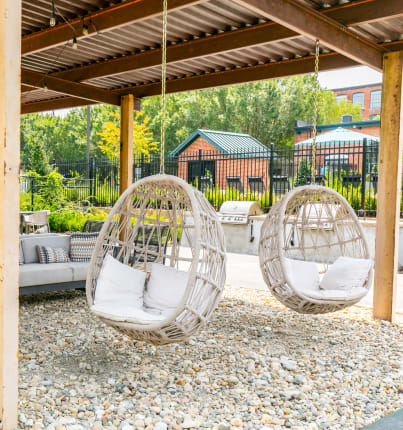 Covered outdoor community space with couch seating and hanging basket chairs at Lofts at Riverwalk in Columbus, Georgia