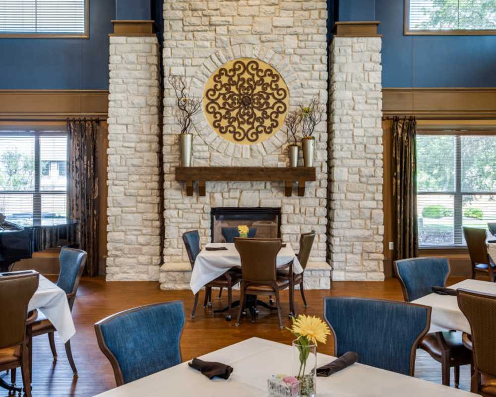 Dining room at Isle at Cedar Ridge in Cedar Park, Texas, with warm tones, large windows, and tree views outside.