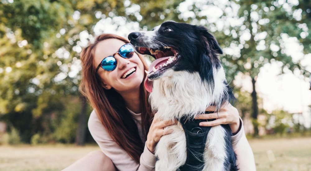 Person smiling, wearing sunglasses, and hugging their dog at Bellrock Upper North in Haltom City, Texas