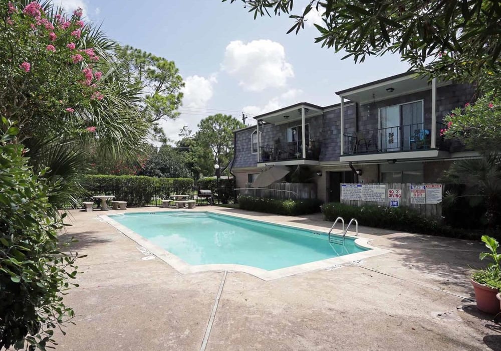 Lush mature trees providing shade at the resort-style swimming pool area at Brittany Place Apartments in Houston, Texas