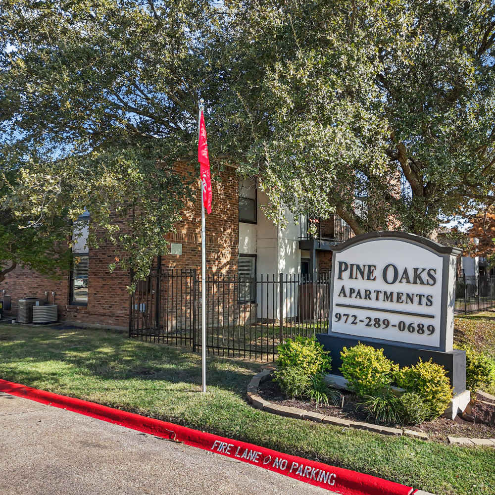 Property signage board at Pine Oaks Apartments in Mesquite, Texas