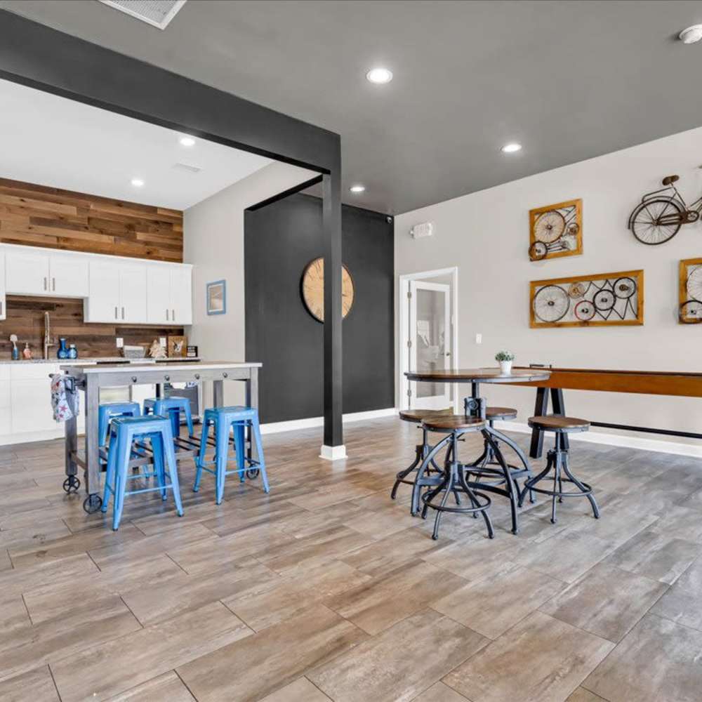Modern community kitchen with wood-style flooring, white cabinets, and blue barstools around an island at 43 North Apartments in Grand Haven, Michigan