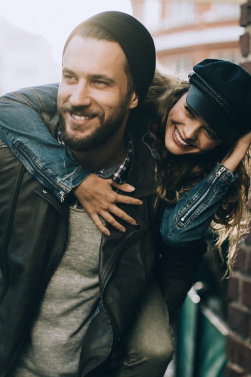 Man giving his partner a piggy back ride through the neighborhood near The Croydon in Washington, District of Columbia