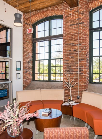 Outdoor lounge chairs by community pool with clubhouse in the background at Loray Mill Lofts in Gastonia, North Carolina