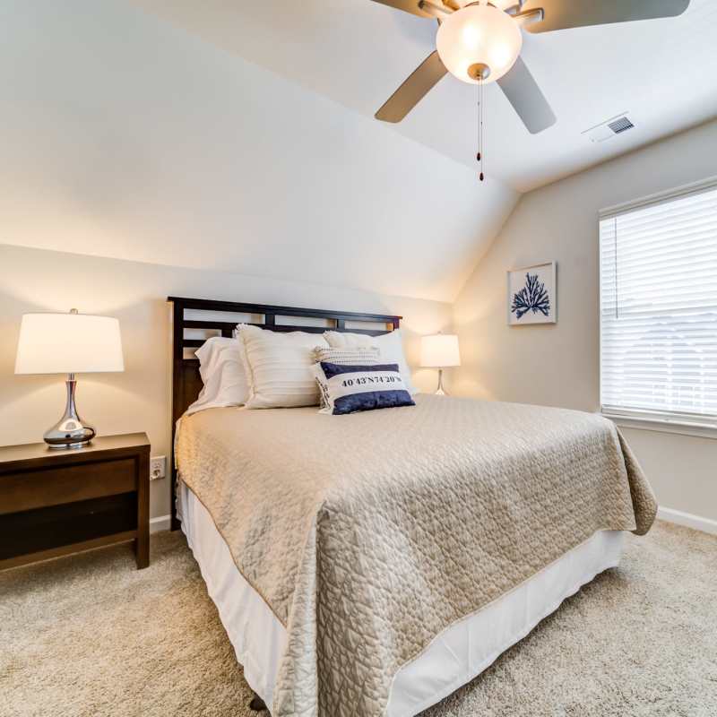 Modern bedroom with ceiling fan and a window at Seaglass Cottage in North Myrtle Beach, South Carolina