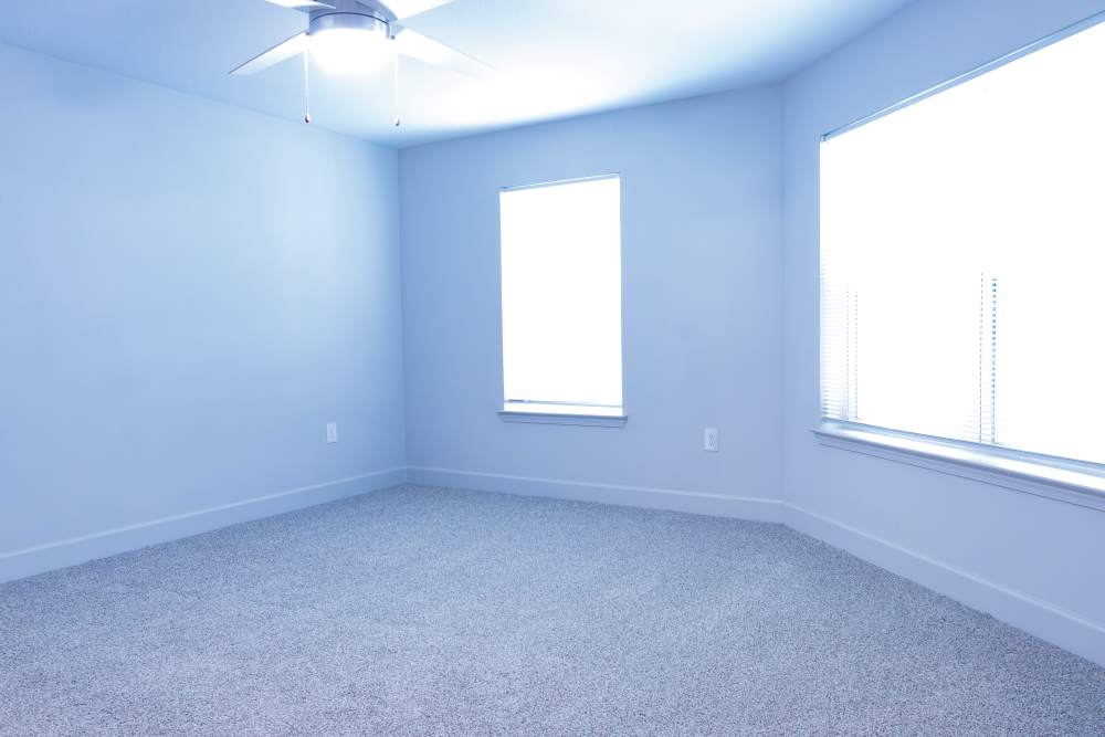 Unfurnished bedroom with ceiling fan, carpet flooring and large window at Villas At Mount Zion in Stockbridge, Georgia