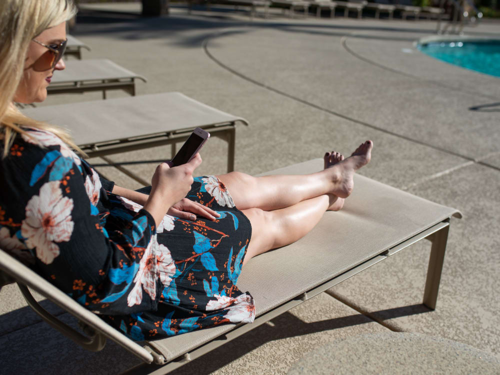 Resident on iPhone enjoying the sun by the poolside at San Palmilla in Tempe, Arizona