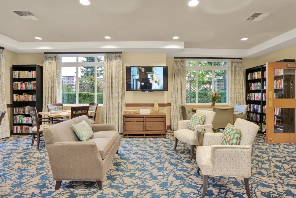 Community media room with shelves of books and furnishings at The Creekside in Woodinville, Washington