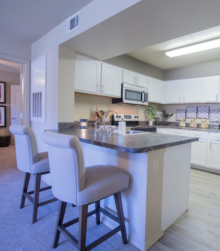 Carpeted living room and kitchen bar at Mission Point Apartments in Moore, Oklahoma