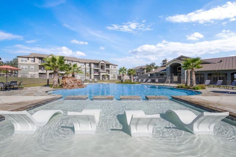 Resort style swimming pool with lounge chairs in the shallow end at Verandas at Alamo Ranch in San Antonio, Texas