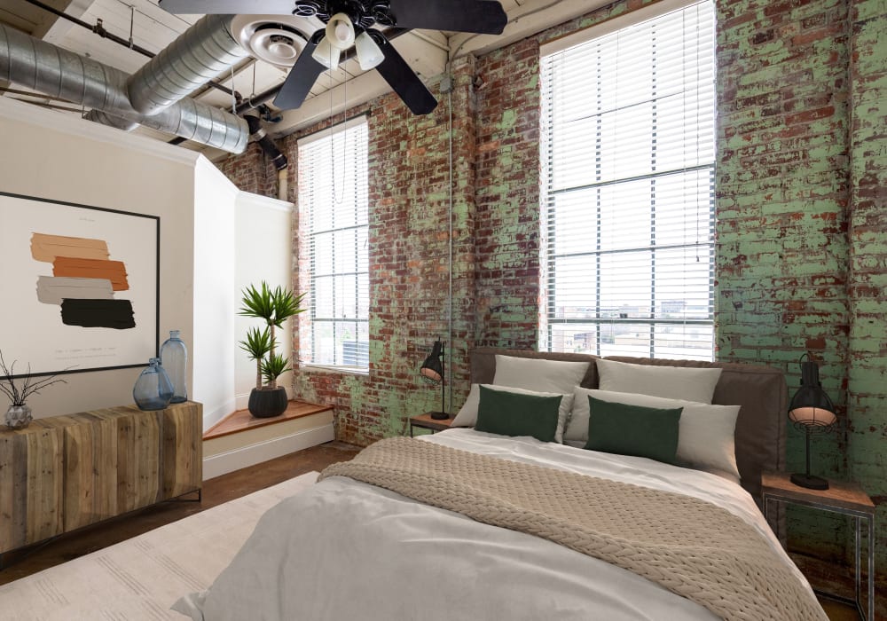Bedroom with exposed brick in a model loft apartment at Broadway Lofts in Macon, Georgia
