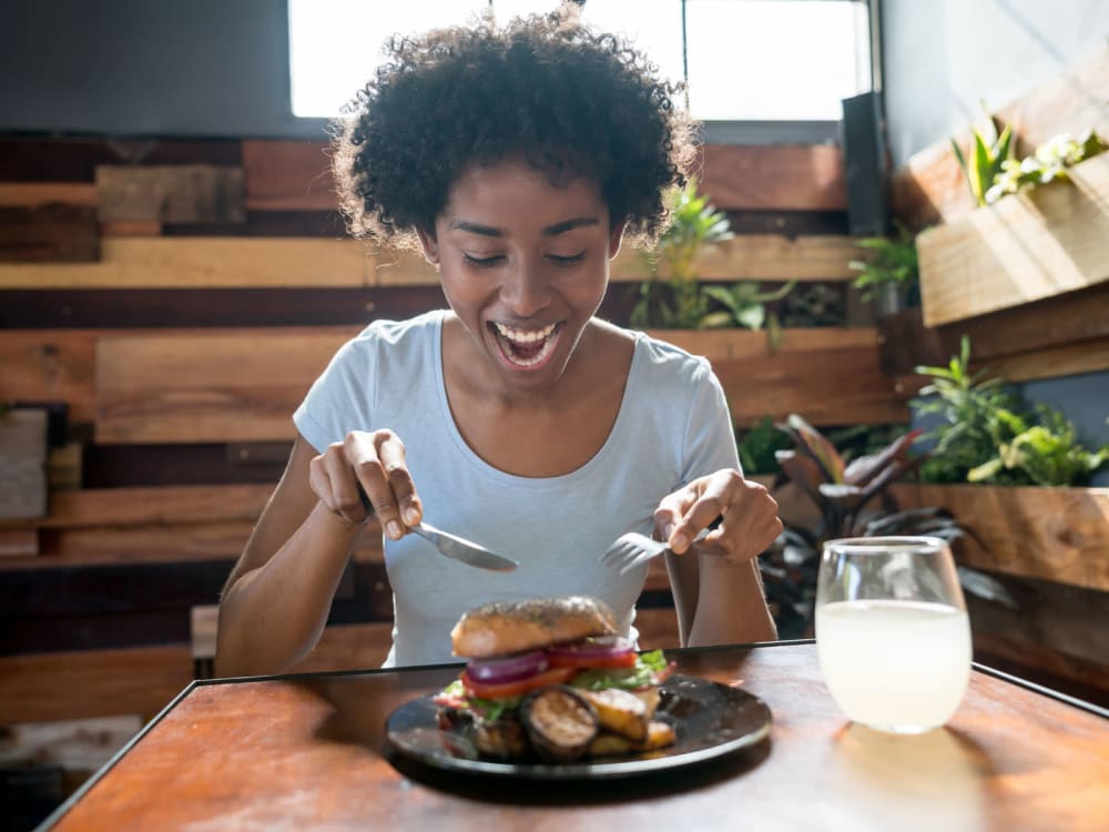 Resident digging into a burger at a restaurant near The Ventura in Chandler, Arizona