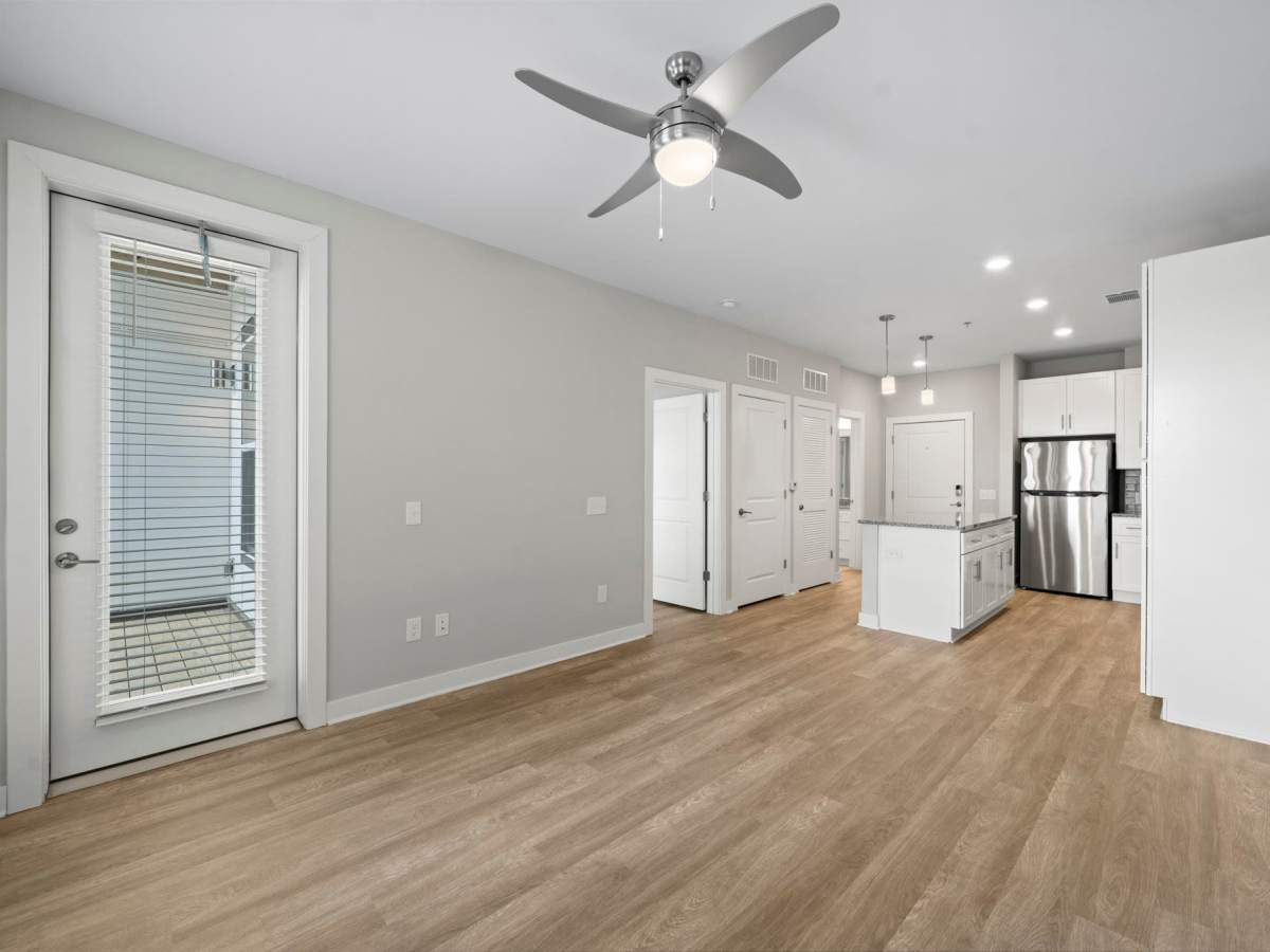 Unfurnished living room with ceiling fan, wood-style flooring and view to kitchen at The Rise at Regency in Henrico, Virginia