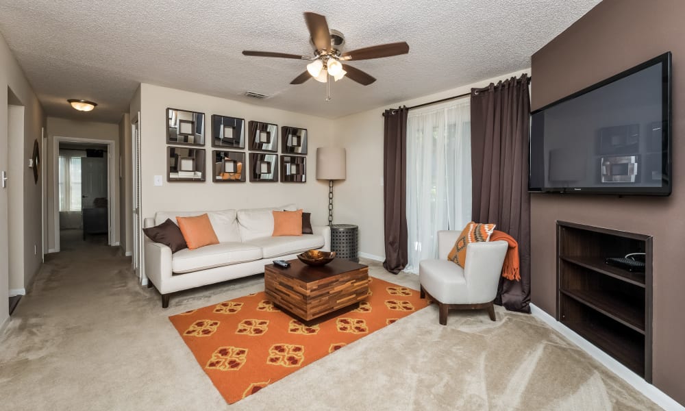 Living room with built-in shelving, wall-to-wall carpeting and a ceiling fan in a model home at Tuscany Pointe at Tampa Apartment Homes in Tampa, Florida