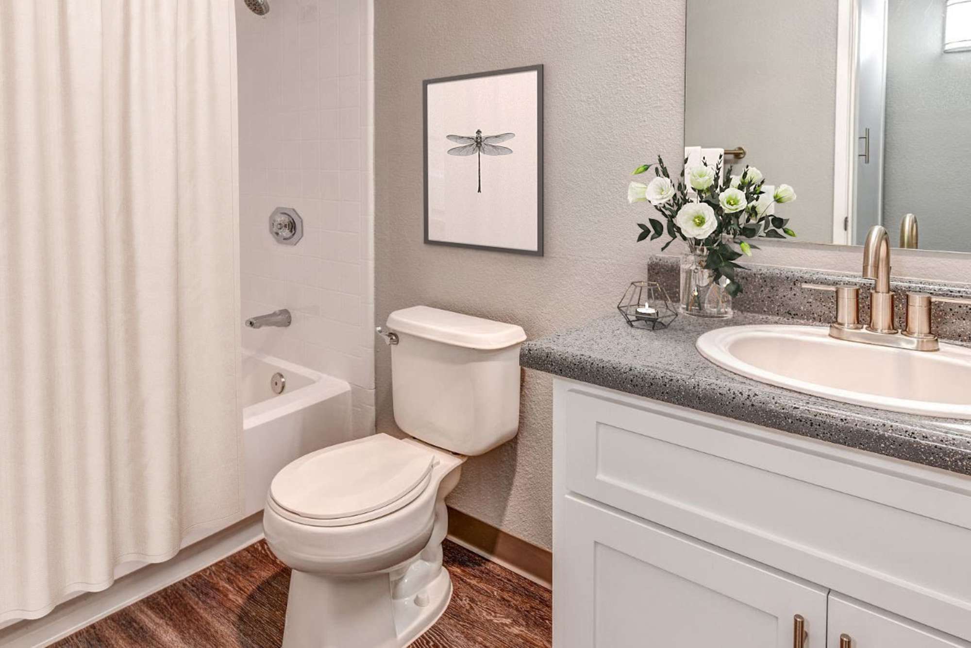 Bathroom with hardwood-style flooring at The Woodlands Apartments in Sacramento, California