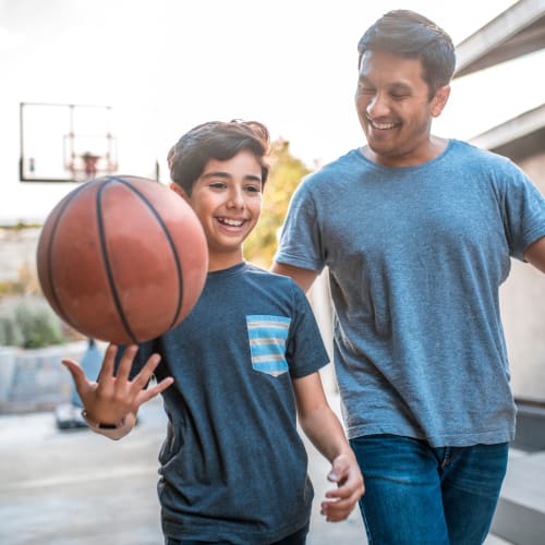 A father and his son walking with a basketball at Howard Gilmore Terrace in La Mesa, California