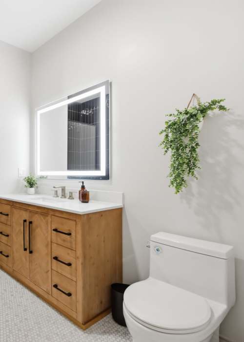 Modern bathroom with wood vanity, mirror, and toilet in clean layout at The Lawrence in Buffalo, New York