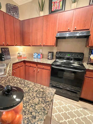Kitchen with black appliances and wood-style cabinets at The Abbey at Stone Oak in San Antonio, Texas