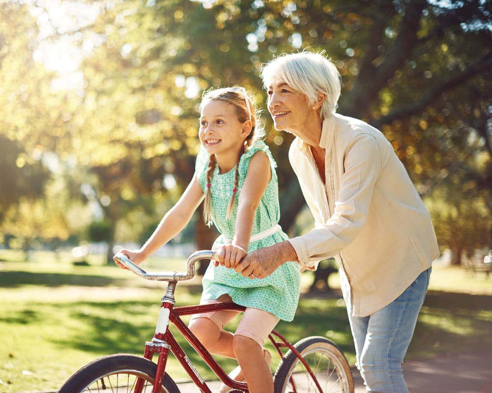 Senior with Granddaughter on bike at The Palisades at Broadmoor Park in Colorado Springs, Colorado