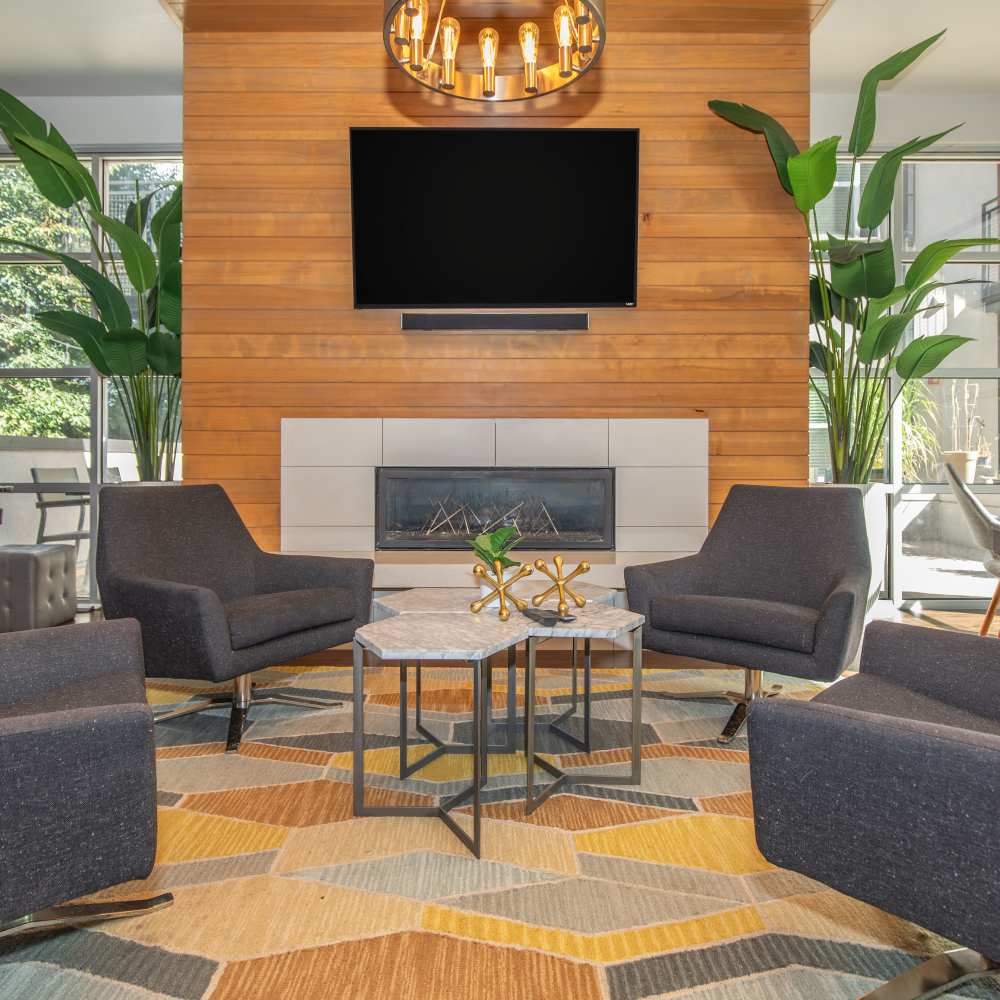 Community clubouse with chairs, tables, fireplace, pendent light and flat screen television at Park Place Olde Town Apartments in Arvada, Colorado