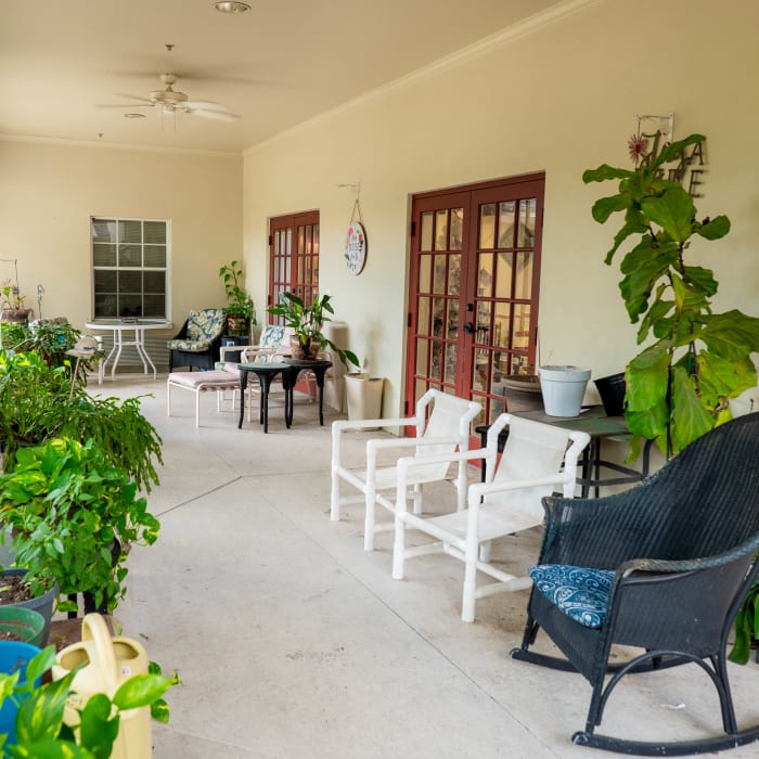 Screened in porch with wicker chairs, tables and potted plants at The Club at Lake Wales in Lake Wales, Florida