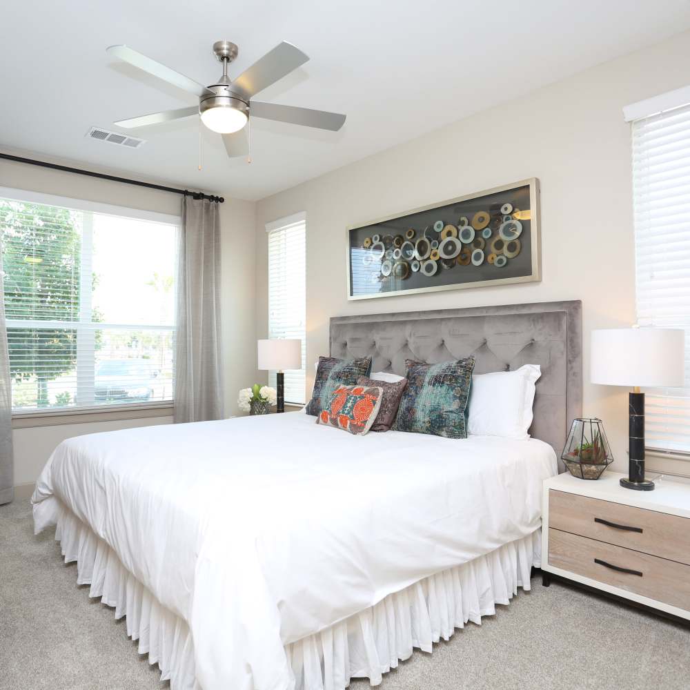 Comfortable bedroom with king size bed, side table lamp, ceiling fan and large window at NOVU New Forest in Houston, Texas