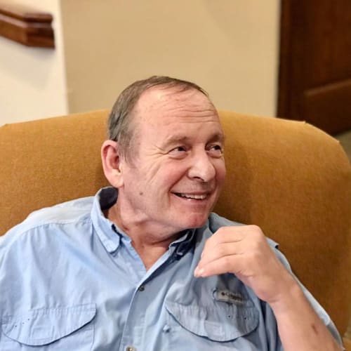 Resident smiling and sitting in a chair at Oxford Glen Memory Care at Carrollton in Carrollton, Texas