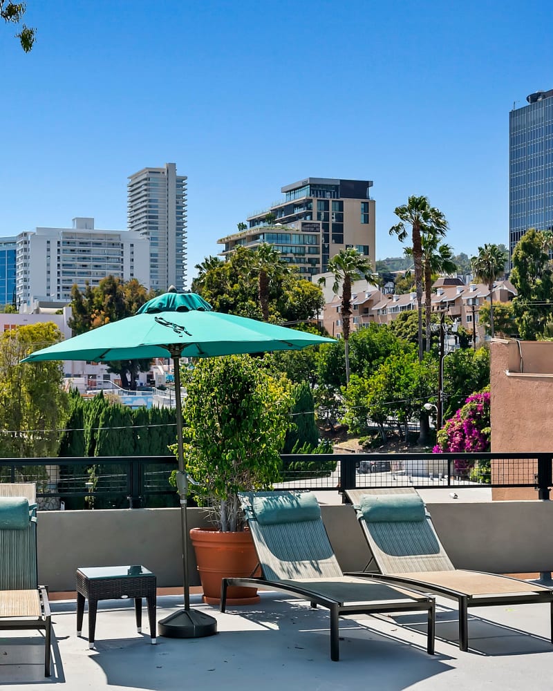 Pool patio with lounge chairs and sun umbrella at Ascent, West Hollywood, California