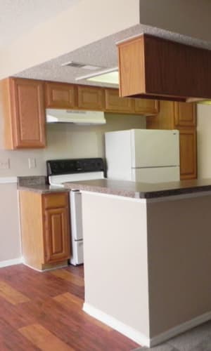 Fully-equipped kitchen with pass-through window and a dining area with wood-style flooring at Baker Square in Mesquite, Texas