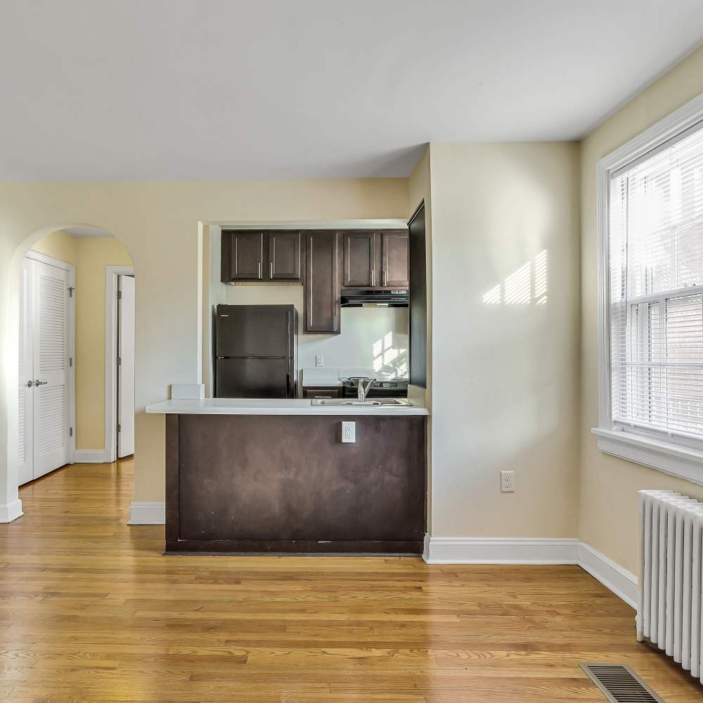 Spacious living area with wood-style flooring, adjacent to the kitchen at Terraces at Bellevue in Richmond, Virginia