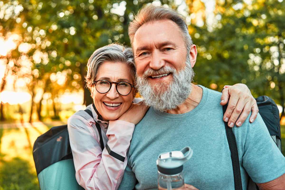 Smiling 55+ couple walking together outdoors on a scenic path surrounded by trees in Conroe Texas
