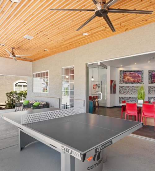 Covered patio seating with ping pong and a TV at Luxe @ Ocotillo in Chandler, Arizona