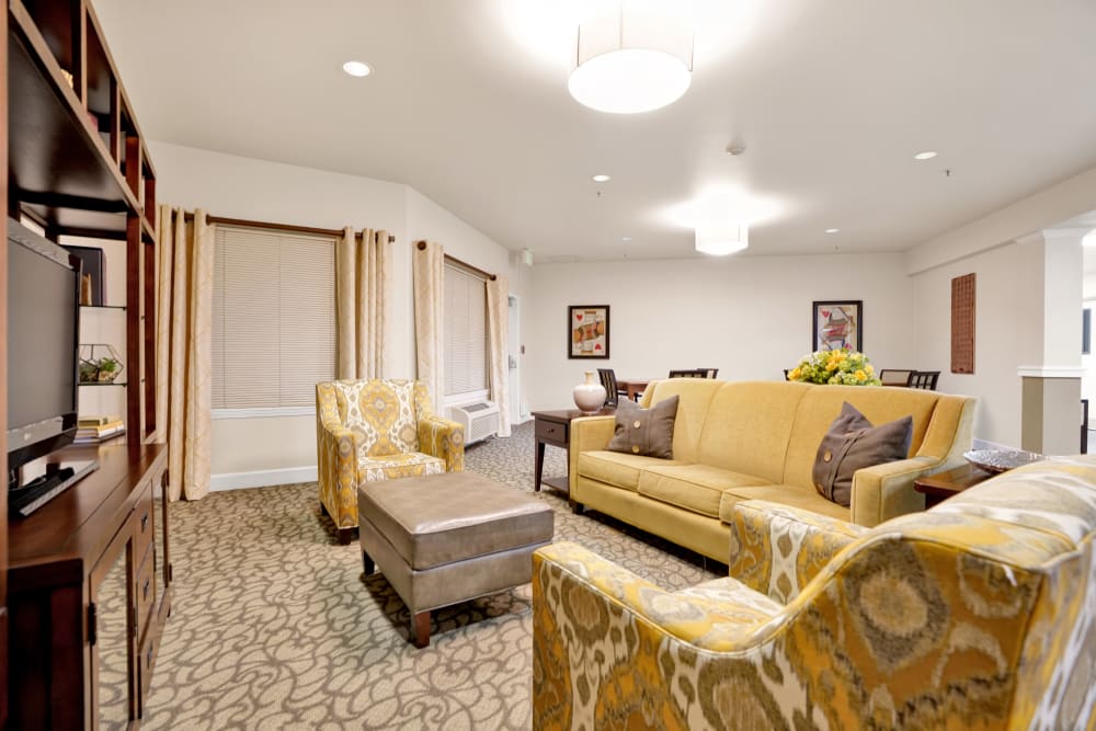 Living room with two chairs and a couch sitting in front of a TV at