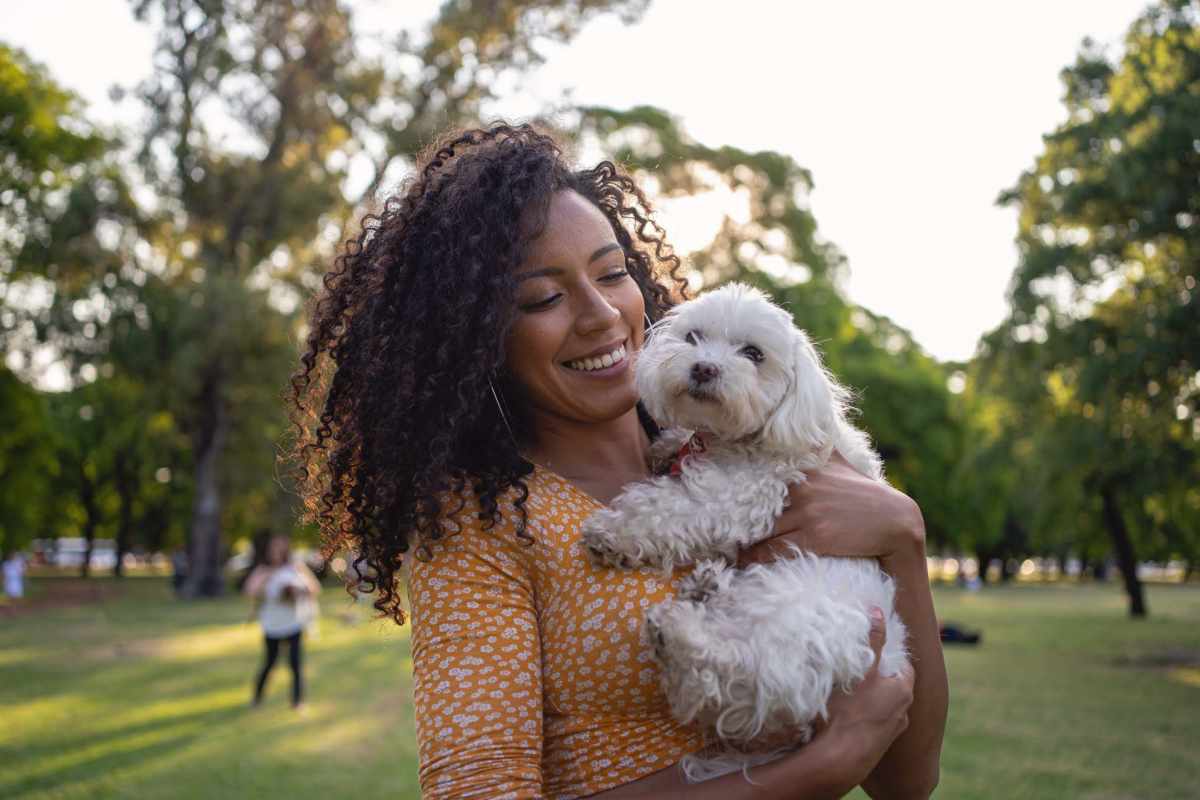 Vibrant park setting featuring a joyful woman with her fluffy dog amidst lush greenery at Charter Oak in Euless, Texas.