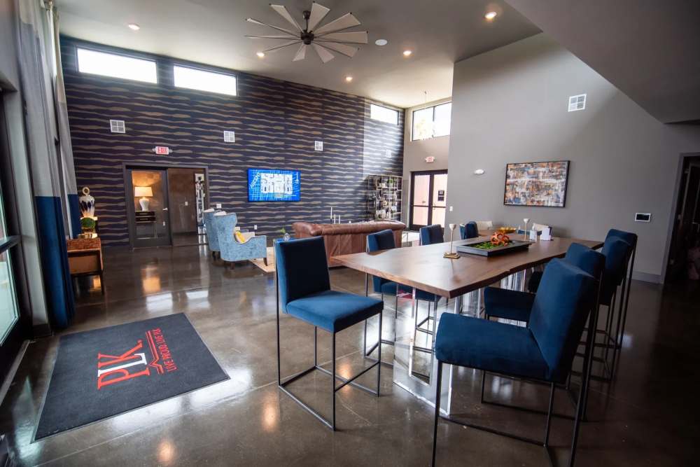 Spacious resident lounge at Elevation 800 featuring modern seating, high ceilings, polished concrete floors, and a large community table with plush blue chairs.