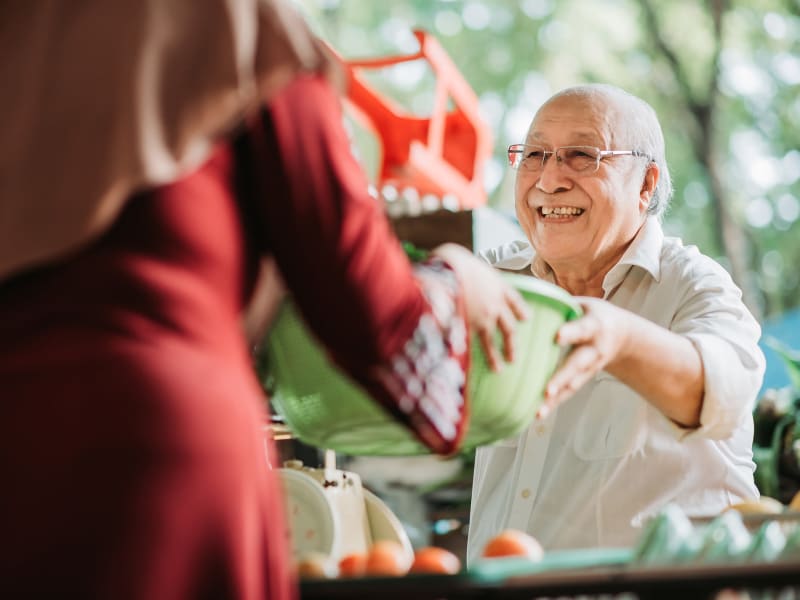 Resident being handed a large plastic bowel of fresh vegetables at Fair Oaks Health Care Center in Crystal Lake, Illinois