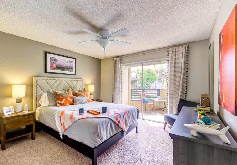 Well-furnished model home's master bedroom with sliding glass doors leading to the private balcony outside at Sofi Irvine in Irvine, California