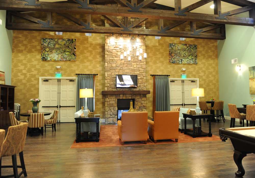 Inviting common area featuring cozy seating, rustic stone fireplace, and elegant artwork, all enhanced by soaring ceilings and warm wooden accents at Cresta Bella in San Diego, California