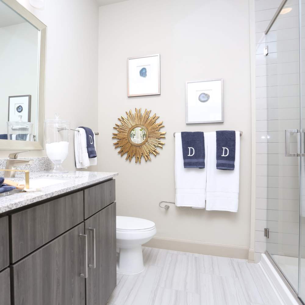 Bright bathroom with mirror, sink, commode and glass shower at NOVU New Forest in Houston, Texas